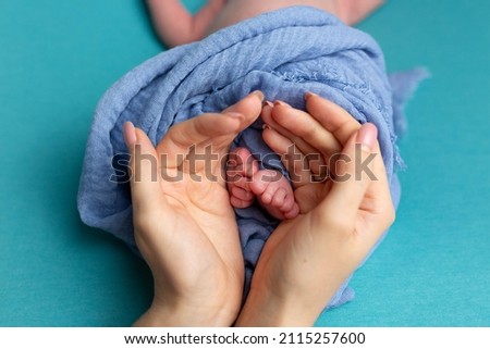 little feet of a newborn baby in mother's hands