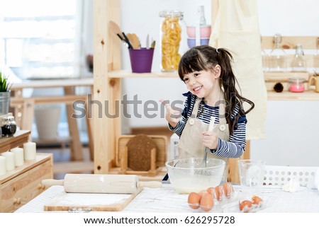Little female chef preparing vegetable soup in kitchen