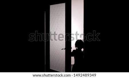 Little female child silhouette opening door into darkness, horror scene, mystic
