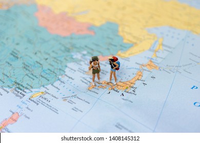 A little figure couple backpacker or miniature couple tourist male and female stand and walk on map of Japan in world map. - Powered by Shutterstock