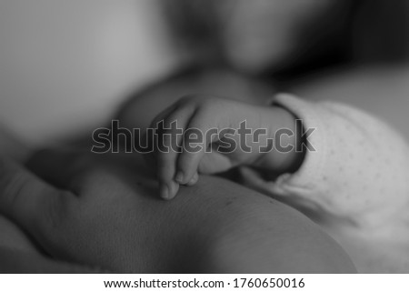 Little fingers of newborn baby with mother's breast. Cute little child with mother's hand. Breastfeeding of Infant. Image with selective focus.