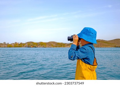 a little fisherman boy looks into a binocole - Powered by Shutterstock