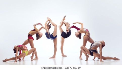 Little flexible girls, rhythmic gymnast athletes training in elegant stage costumes against white studio background. Concept of choreography, hobby, art, sport, childhood, performance - Powered by Shutterstock