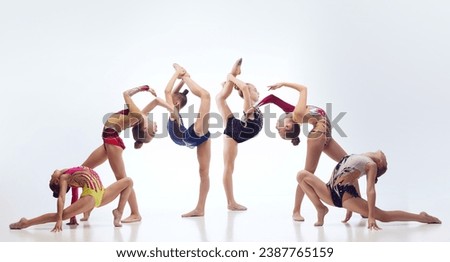 Little flexible girls, rhythmic gymnast athletes training in elegant stage costumes against white studio background. Concept of choreography, hobby, art, sport, childhood, performance