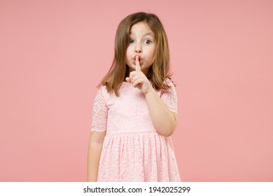 Little fun kid girl 5-6 years old wears rosy dress say secret hush be quiet with finger on lips shhh gesture isolated on pastel pink background child studio portrait. Mother's Day love family concept