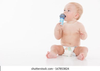 Little Funny Baby Holding Microphone And Looking At Copy Space. While Sitting Isolated Over White Background 