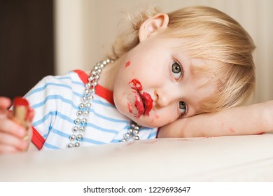 Little Funny Blond Baby Girl Make Up Lips With Mom's Red Lipstick. Learning To Be Woman. Happy Childhood Concept. 