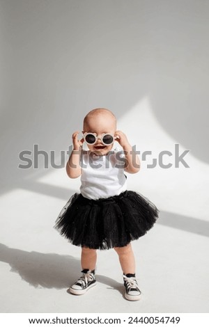 Little funny girl (1 year old) posing in sunglasses in a photo studio
