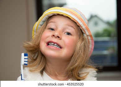 little funny girl with retainer and toothbrush looking in to the camera