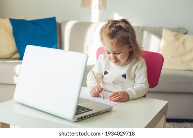 A little girl of 3 years old is studying online. The little girl draws. Quarantine. Online. - Powered by Shutterstock