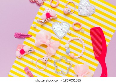 Little Girl Accessories Lifestyle Set On Lilac And Yellow Striped Background. Hair Clips, Hairpins, Bow Tie On Pink Background. Fashion Hair Accessories For Little Girls. Flat Lay.