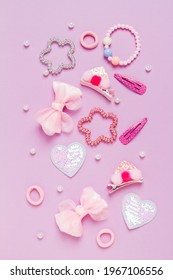 Little Girl Accessories Lifestyle Set On Lilac Background. Hair Clips, Hairpins, Bow Tie On Pink Background. Fashion Hair Accessories For Little Girls. Flat Lay.