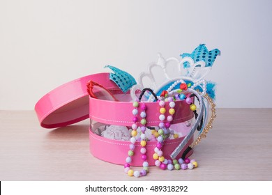 Little Girl Accessories Lifestyle Set In A Pink Box. Headbands, Necklace,eye Wear On Wood Table.