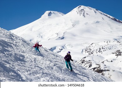 Little girl and an adult woman skiing in the mountains against Mount Elbrus. In sunny weather.