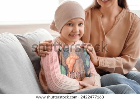 Little girl after chemotherapy with book and her mother at home. International Childhood Cancer Day
