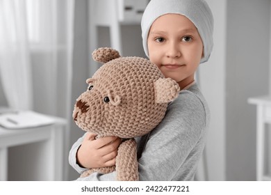 Little girl after chemotherapy with toy bear in clinic, closeup. International Childhood Cancer Day
