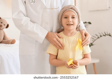 Little girl after chemotherapy with yellow ribbons and doctor in clinic. Childhood cancer awareness concept - Powered by Shutterstock