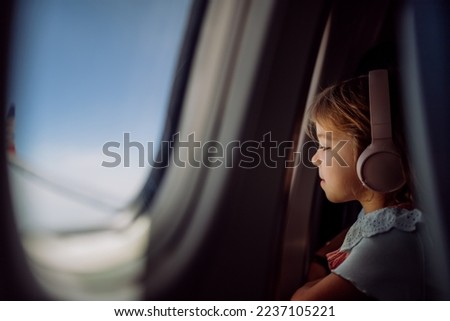 Little girl in airplane looking out of the window.