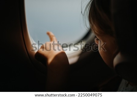 Little girl in airplane looking out of the window.