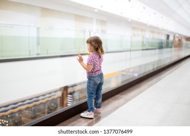 Little Girl Alone In Shopping Mall Center, Looking For Her Mother. The Child Was Lost In The Big Store.