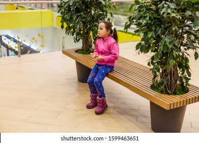 Little Girl Alone In Shopping Mall Center, Looking For Her Mother. The Child Was Lost In The Big Store.