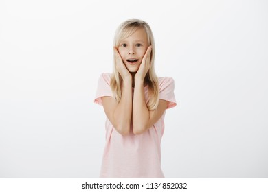 Little Girl Amazed With Huge Shark Swimming In Aquarium. Portrait Of Excited Astonished Cute Child With Fair Hair, Holding Palms On Cheeks And Dropping Jaw, Seeing Unbelievable Great Toy In Store