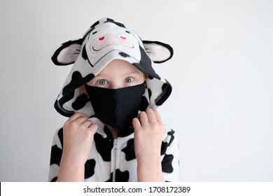 Little Girl In Animal Pajamas And Protective Face Mask. Pajana Cow Wearing A Baby