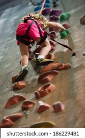 Little Girl Ascending In Indoor Rock Climbing Gym.