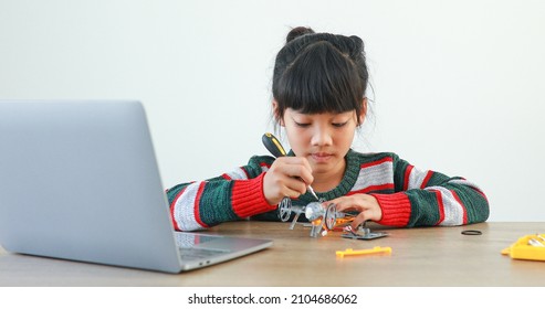 The little girl asian building robotic car in science lesson in the house . Which increases the development and enhances learning skills gifted brilliant children working with technology. - Shutterstock ID 2104686062
