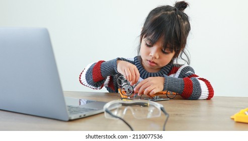 The little girl asian building robotic car in science lesson in the house . Which increases the development and enhances learning skills gifted brilliant children working with technology. - Shutterstock ID 2110077536