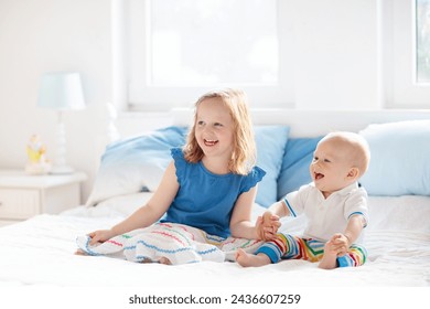 Little girl and baby boy, brother and sister playing in parents bed. Family with children in the morning. Kids play in white bedroom. Nursery crib bedding and textile for young child. Siblings love. - Powered by Shutterstock