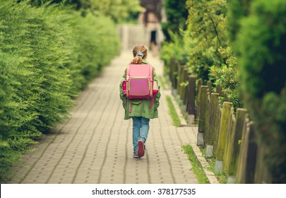 Little Girl With A Backpack Going To School. Back View