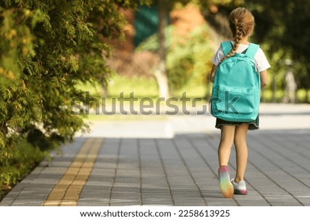 Little girl with backpack going to school, back view. Space for text