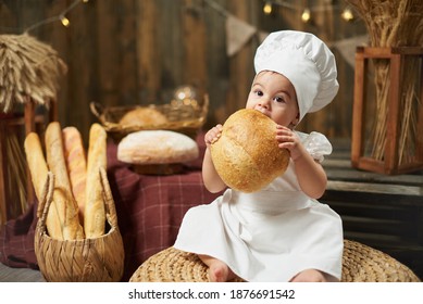 Little Girl Baker Eating Fresh Round Bread