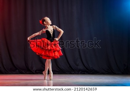 little girl ballerina is dancing on stage in tutu on pointe shoes with castanedas, the classic variation of Kitri.
