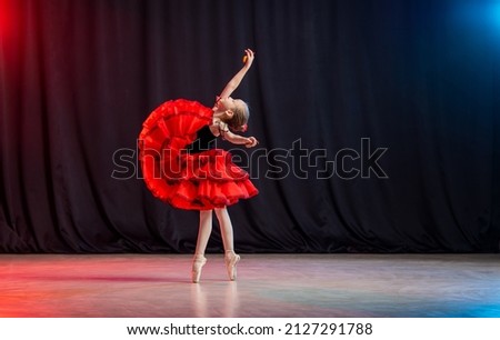 little girl ballerina is dancing on stage in tutu on pointe shoes with castanedas, the classic variation of Kitri.