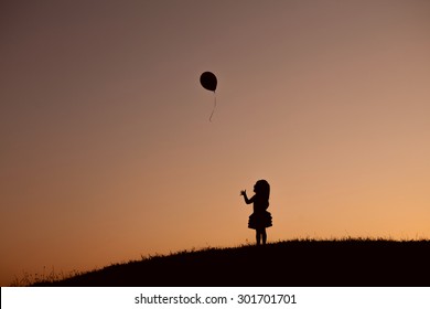 little girl with balloon in the park at sunset