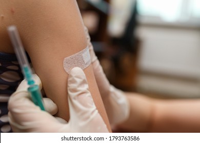 Little girl with band aid on the shoulder from the injection. Vaccinated in the arm. Prevention of children diseases through vaccination. Health care and medicine concept. Focus on shoulder.