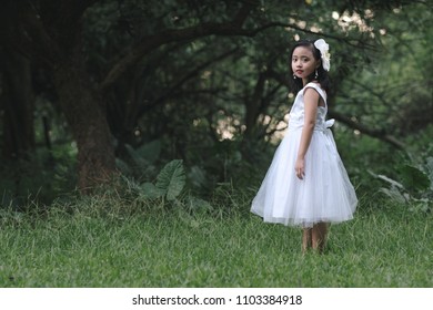 Little girl in a beautiful dress in a garden at sunset in Hanoi, Vietnam.