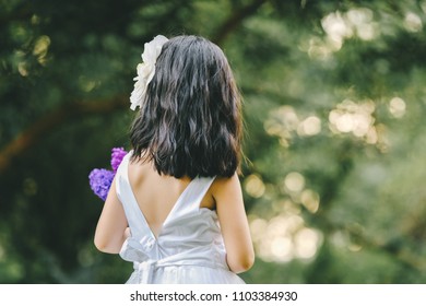 Little girl in a beautiful dress in a garden at sunset in Hanoi, Vietnam.