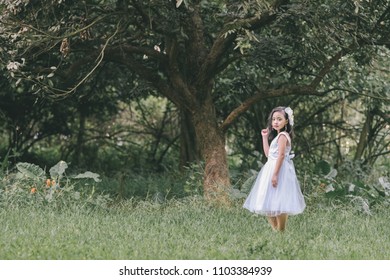 Little girl in a beautiful dress in a garden at sunset in Hanoi, Vietnam.