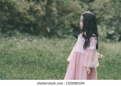 Little girl in a beautiful dress in a garden at sunset in Hanoi, Vietnam.