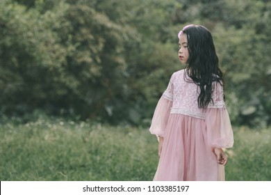 Little girl in a beautiful dress in a garden at sunset in Hanoi, Vietnam.