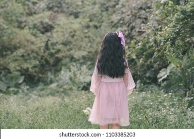 Little girl in a beautiful dress in a garden at sunset in Hanoi, Vietnam.