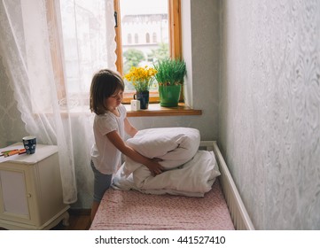 little girl in the bedroom. pretty little girl fold blanket. girl woke up. time to wake up
