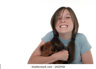 Little Girl With Big, Cheshire Cat Grin, Smiling And Sitting On Floor Holding A Teddy Bear.  Shot On White.