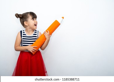 Little girl with big pencil write on wall