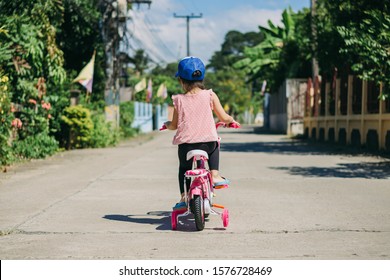 Little Girl Bikes A Bicycle With Training Wheels. Sport And Recreation Outdoor For Kids And Parents.