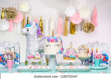 Little girl birthday party table with unicorn cake, cupcakes, and sugaer cookies.