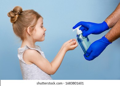 A little girl with blond hair de-sanitizes her hands. Gloved hands pour liquid soap into the child's hands. Security from diseases and viruses. - Powered by Shutterstock